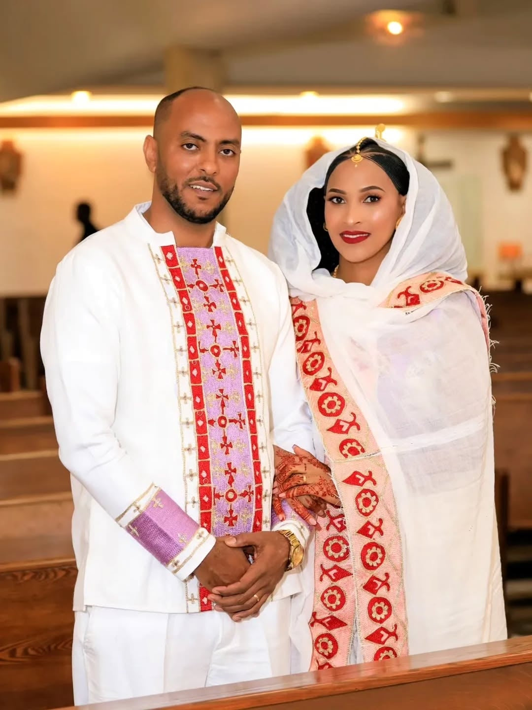 Man and woman in traditional Pink Ethiopian Traditional Dress standing together in a church setting