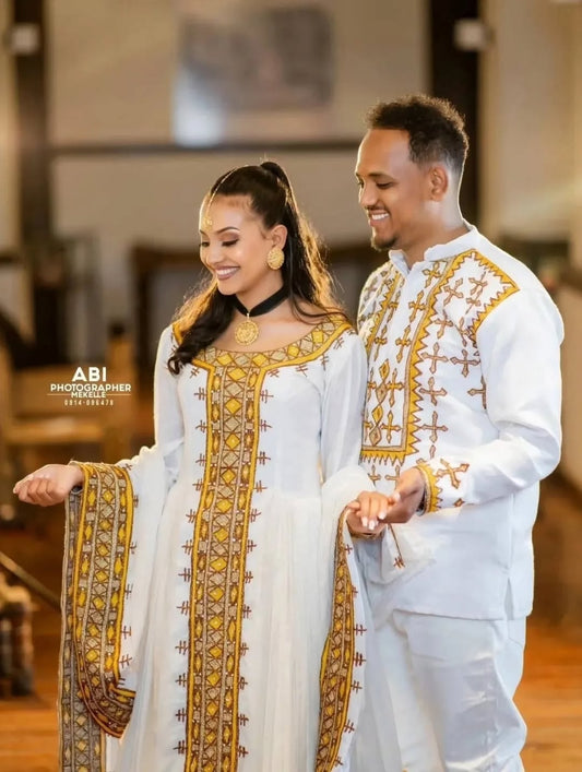 Couple in traditional embroidered Habesha Libs Matching Couple Set  standing close together indoors.
