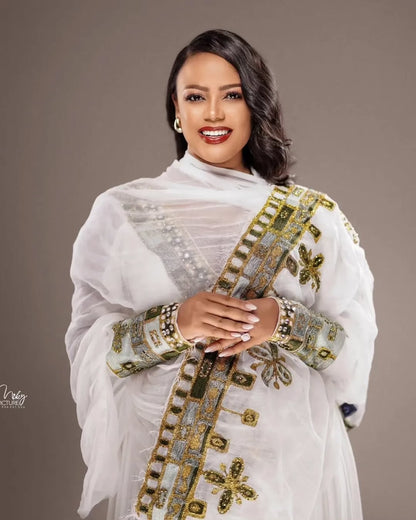 Woman wearing a white embroidered traditional outfit against a brown background