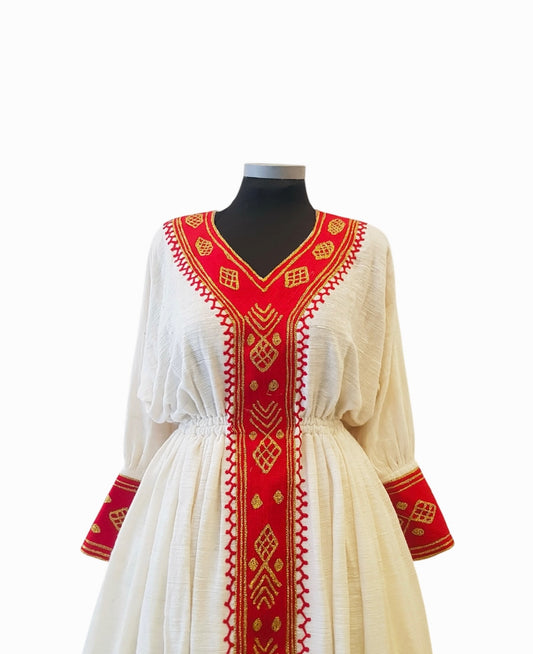 A white long-sleeve Ethiopian Outfit displayed on a black mannequin torso against a plain white background. The dress features prominent red embroidered trim along the V-neckline, center front panel, cuffs, and hem, with gold geometric patterns woven into the red embroidery.