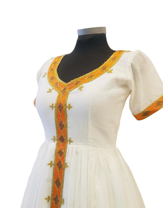 A white short-sleeved Ethiopian Outfit displayed on a black mannequin torso against a plain white background. The dress features ornate orange and gold embroidered trim along the V-neckline, center front placket, and sleeve cuffs.
