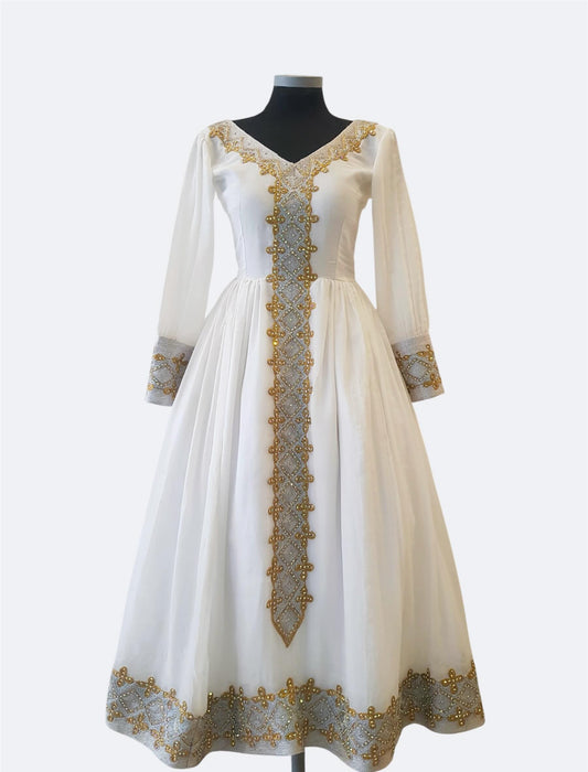 A long white or ivory Ethiopian Outfit displayed on a black mannequin against a light gray studio background. The dress has three-quarter sleeves, a V-neckline, and ornate gold embroidery running down the center front and around the cuffs and hem.