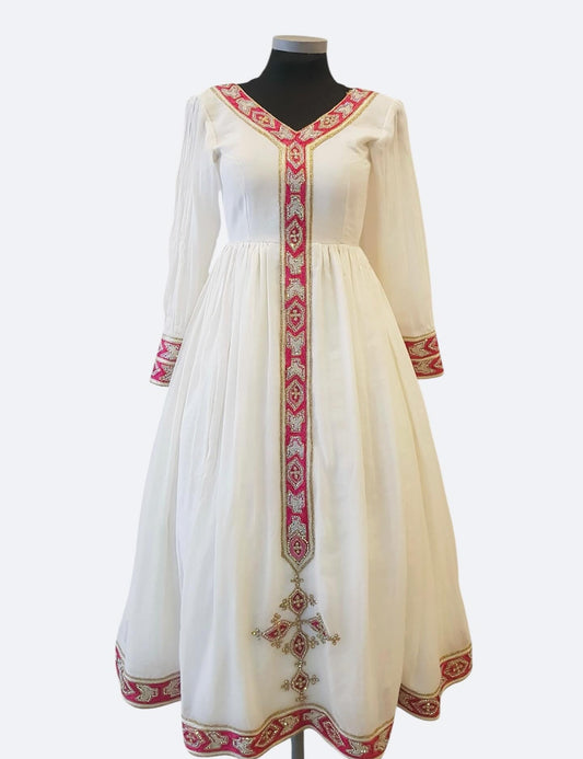 An off-white long-sleeved Ethiopian Outfit  displayed on a black mannequin torso, featuring red and gold geometric embroidery along the V-neckline, cuffs, and hem.