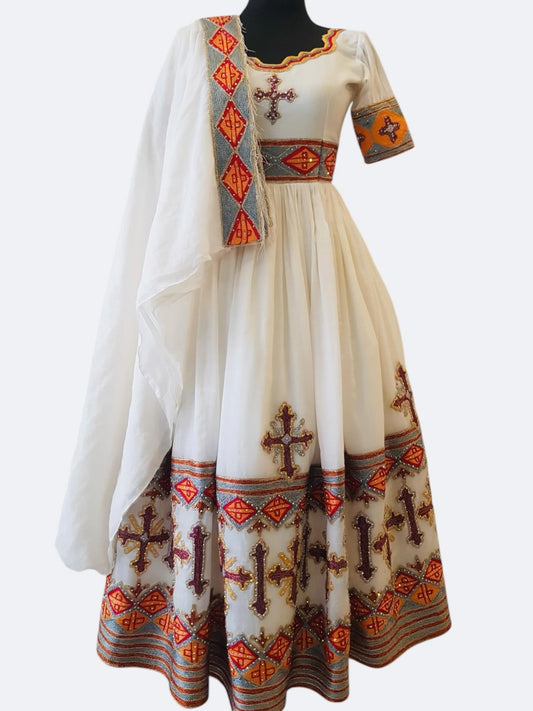 A traditional white Ethiopian outfit  with orange, red, and brown embroidered patterns, featuring a matching sheer white dupatta draped over the shoulders, displayed on a black mannequin against a light gray background.