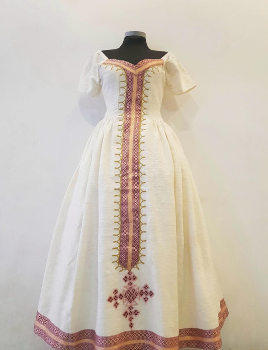 An off-the-shoulder white linen Ethiopian Outfitwith traditional embroidered details, displayed on a black mannequin torso against a plain light background.