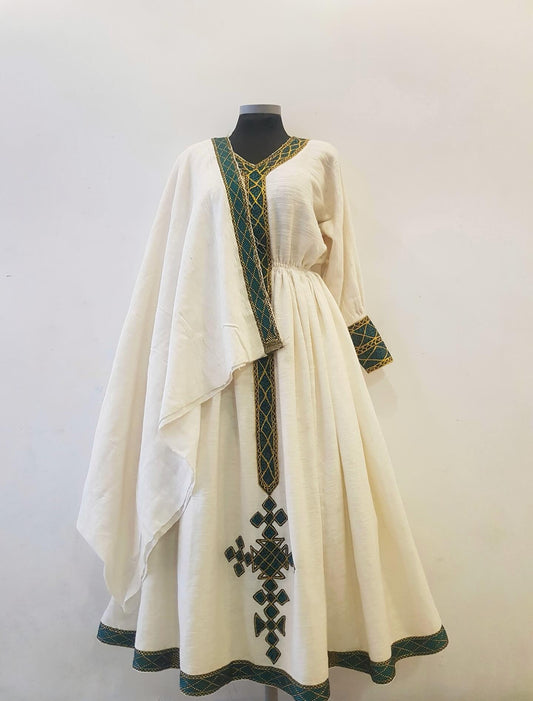 An off-white linen caftan Ethiopian outfit  with green and gold embroidered details, displayed on a black mannequin against a plain light background.
