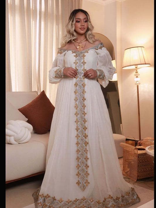 Woman in a white and gold habesha dress in an elegant interior setting.