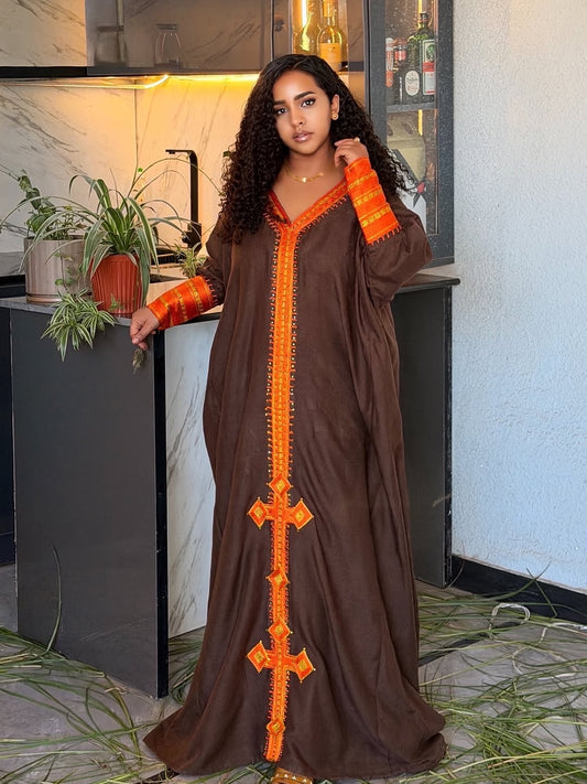 Woman wearing a brown dress with orange accents in a kitchen setting