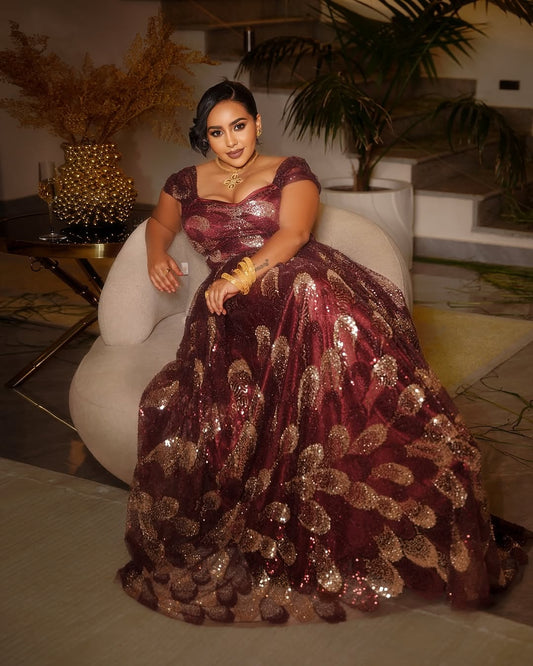 Woman in a sparkling habesha chiffion dress sitting on a chair in an indoor setting