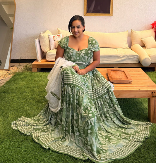 Woman in a green and white patterned Habesha Chiffon sitting on grass in a living room.