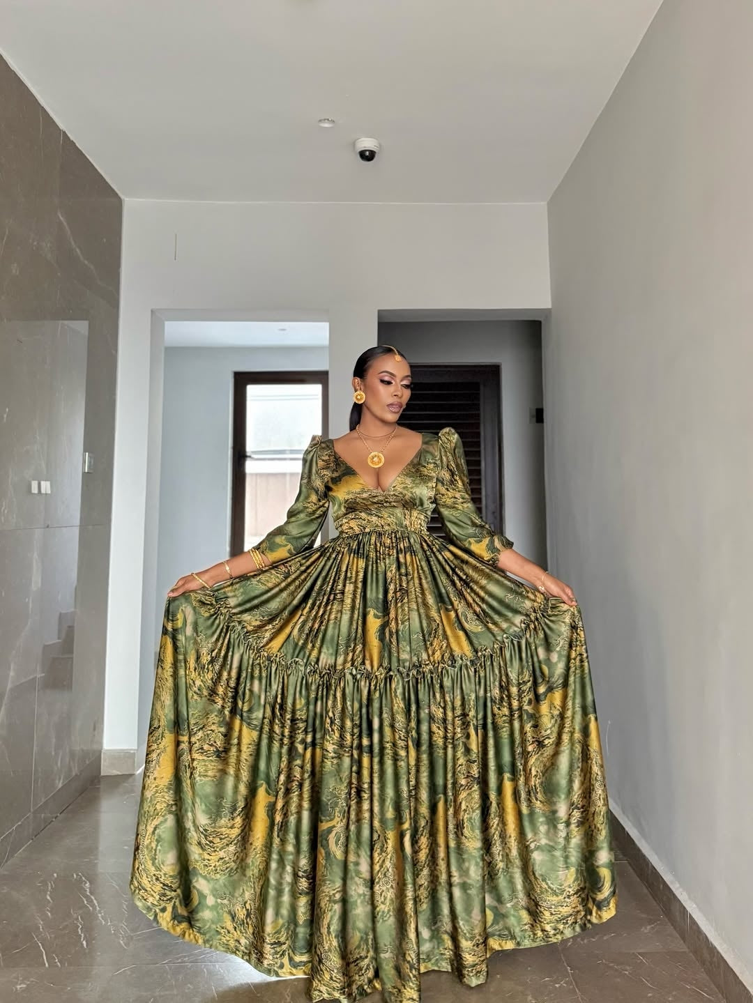 Woman wearing a green and yellow patterned Green Flowing Habesha Shiffon Dress in a modern hallway.