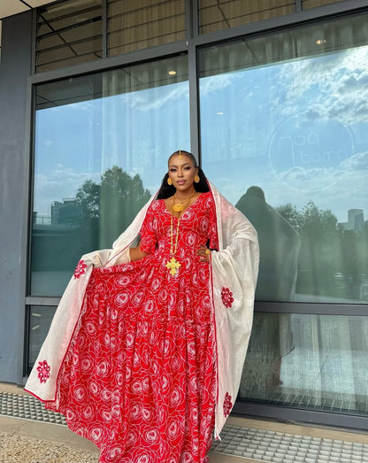 Woman in a red and white traditional outfit standing in front of a glass building.