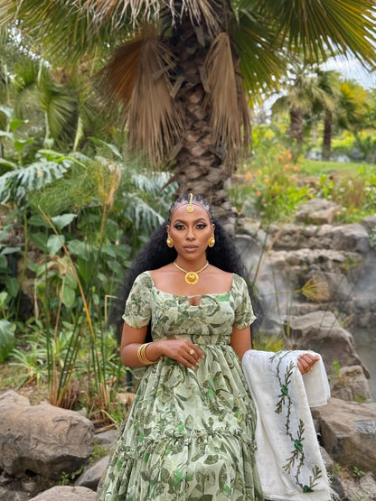 Woman in a Shiffion dress  dress standing in a natural setting with rocks and plants.