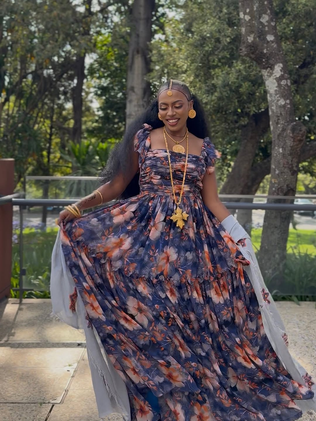 Woman in a Purple Habesha Shiffion standing outdoors with trees in the background