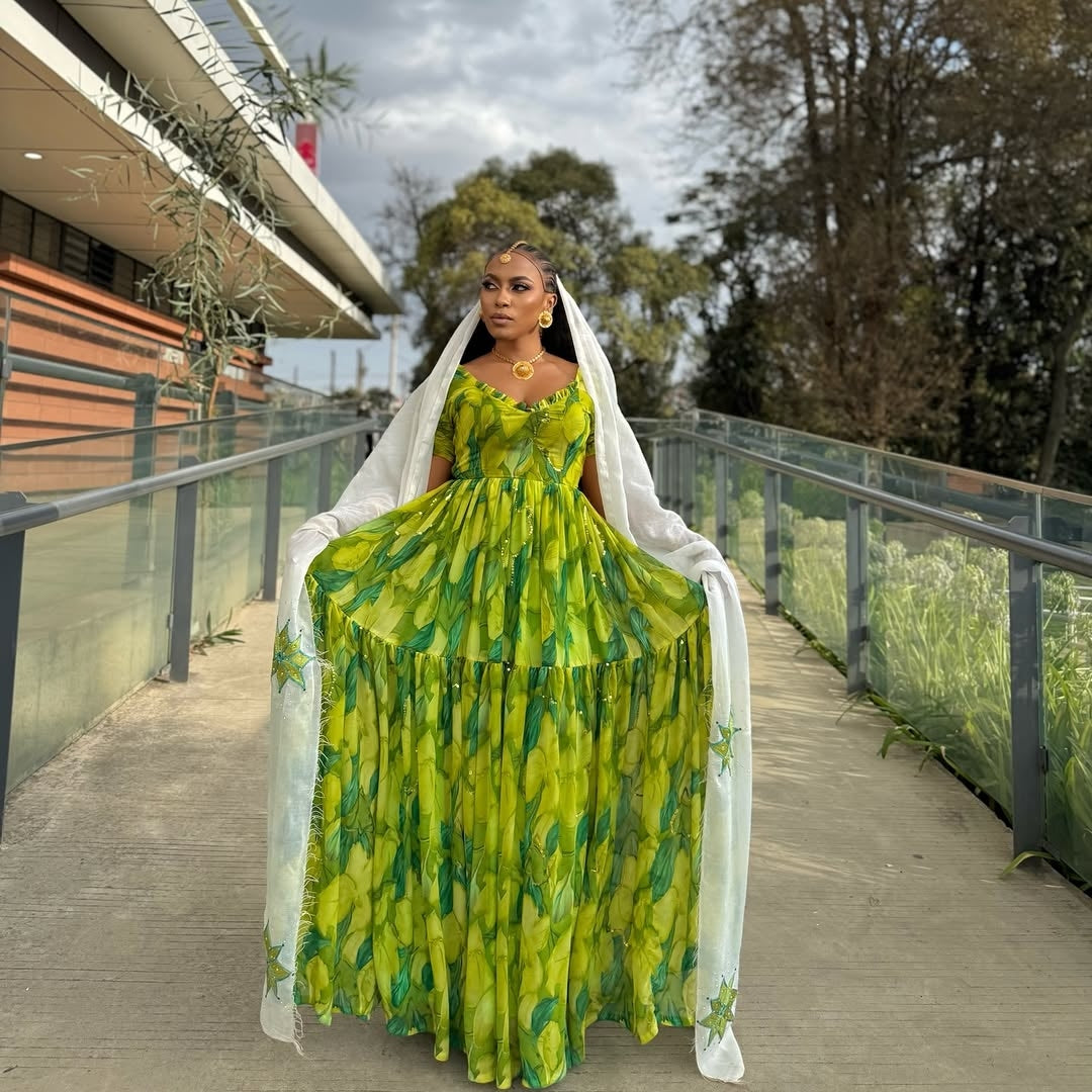 Woman in a Green Habesha Shiffion with a white scarf standing on a wooden bridge.
