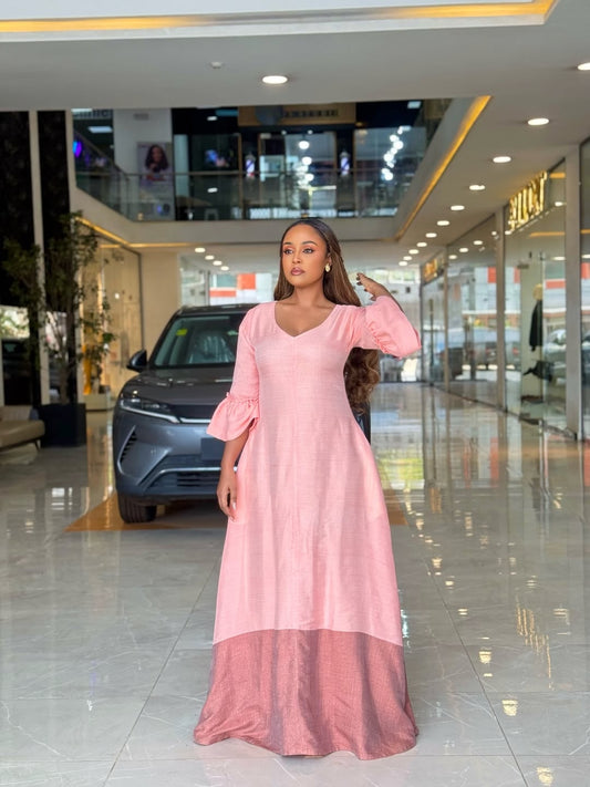 Woman in a pink Ethiopian libs  standing in a modern indoor setting with a car in the background