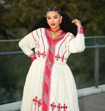 Woman wearing a white Ethiopian Dress with red patterns outdoors