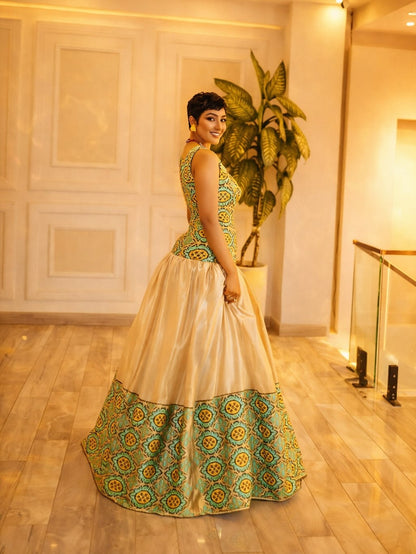 Woman in a traditional Habesha Libs standing indoors with decorative elements.