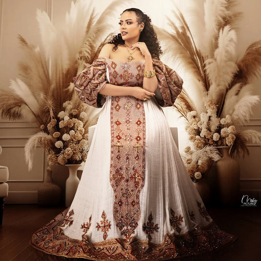 Woman in an embroidered Ethiopian Dress  standing among pampas grass and flowers.