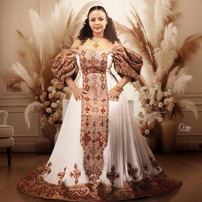 Woman in an ornate Ethiopian Dress  standing in a decorated room with pampas grass.