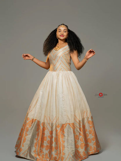 Woman wearing a long, patterned habesha dress against a gray background