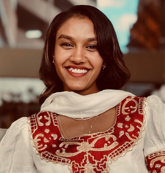Woman wearing a traditional outfit with red and gold Red Habesha Kemis
