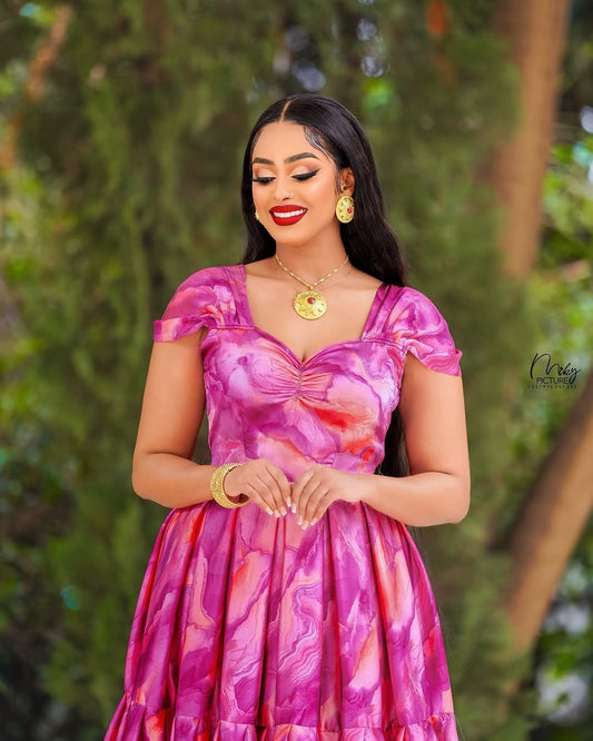 Woman wearing a pink floral habesha chiffion with a green leafy background 