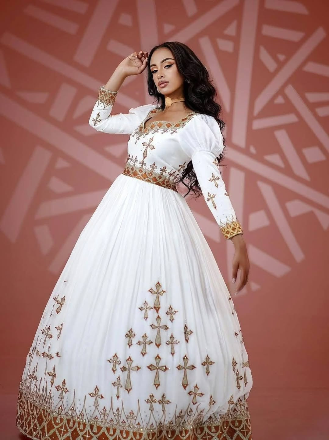 Woman wearing a white Habesha Dress with gold embroidery against a patterned background