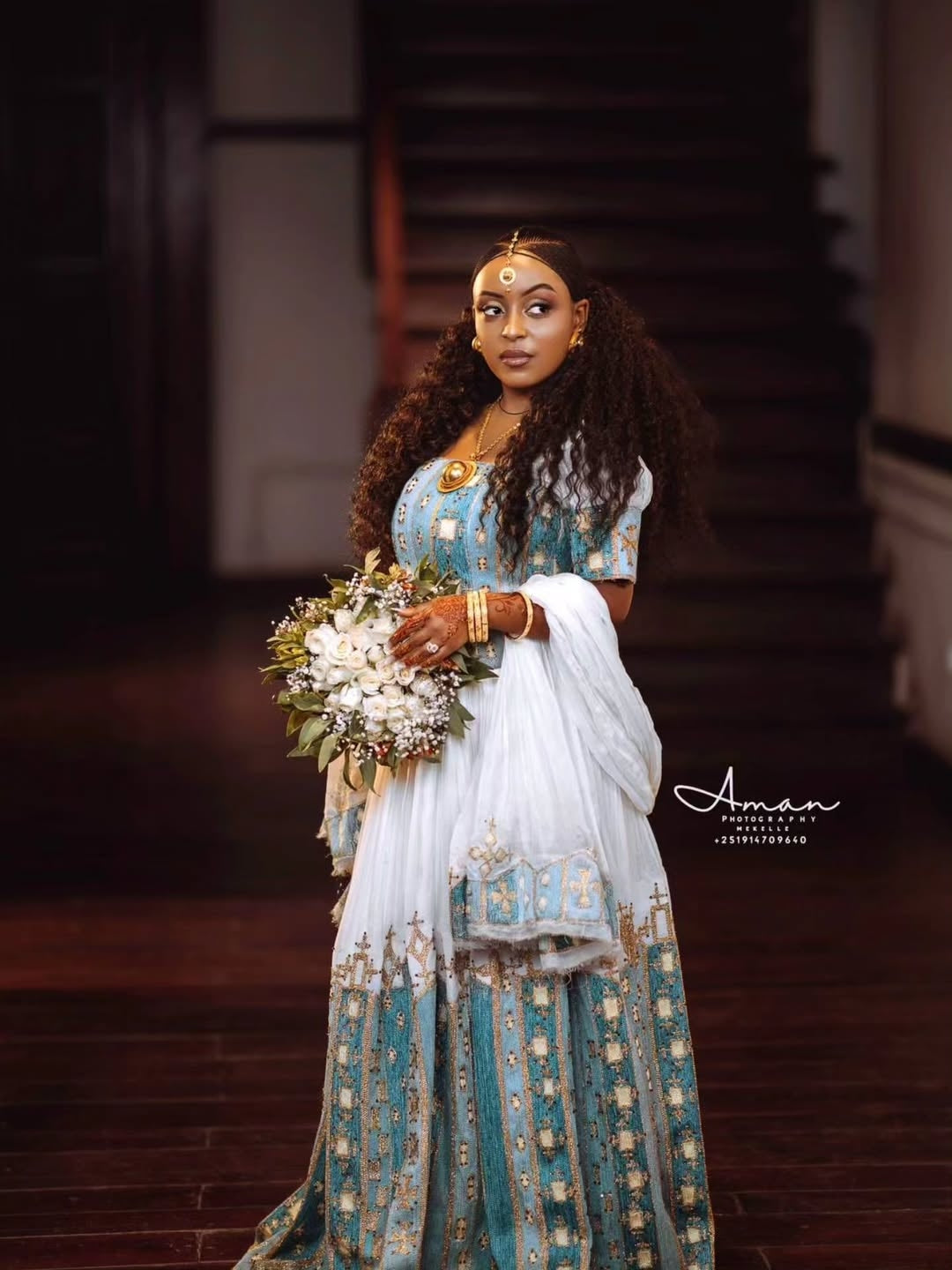 Woman in a traditional Green Ethiopian Couple Matching Set holding flowers indoors