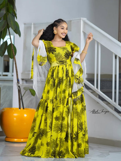 Woman in a Yellow Habesha Shifion standing indoors with a white railing and plant in the background