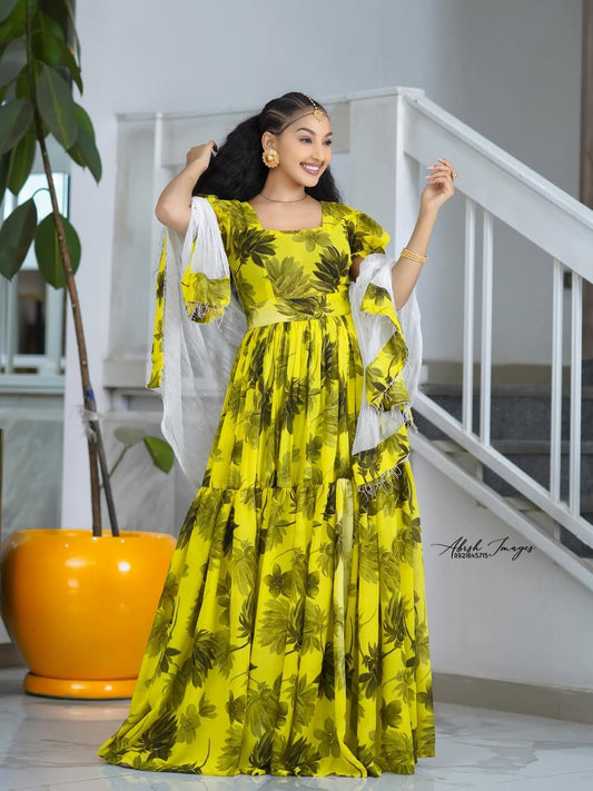 Woman in a Yellow Habesha Shifion standing indoors with a white railing and plant in the background