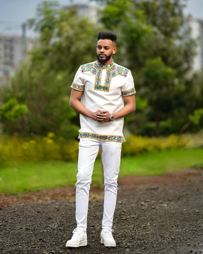 Man wearing a Habesha Men’s Outfit embroidered  with a blurred natural background
