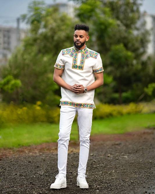 Man wearing a Habesha Men’s Outfit embroidered  with a blurred natural background