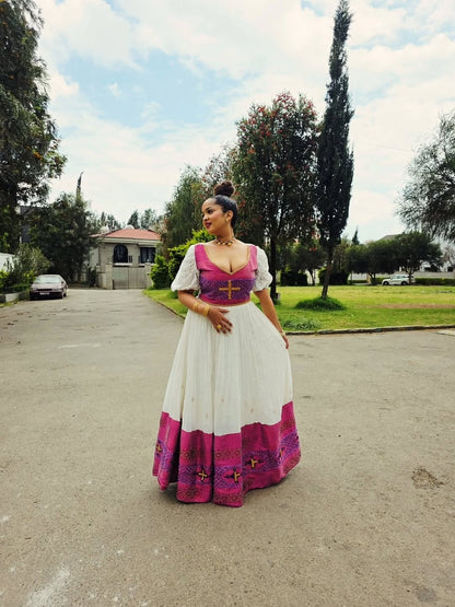 Woman in a traditional Gondar Fetel Dress standing on a street with trees and buildings in the background