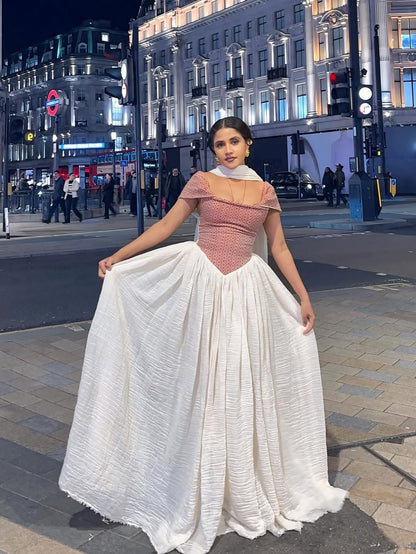 Woman in a red and white Red Off Shoulder Flowing Habesha Zuria standing on a city street at night.