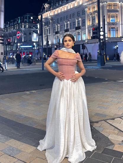 Woman in a red top and white Red Off Shoulder Flowing Habesha Zuria standing on a city street at night.