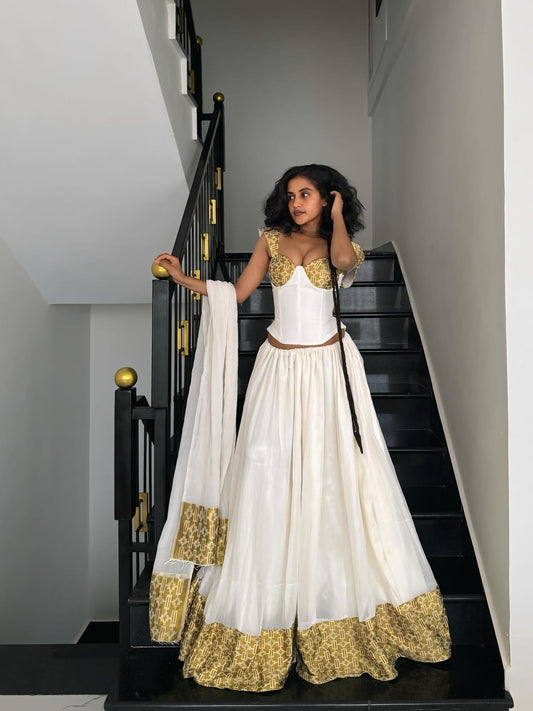 Woman in a white and gold traditional Habesha dress standing on a staircase.