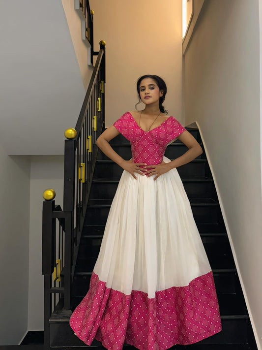 Woman wearing a pink and white traditional habesha Dress standing on a staircase.