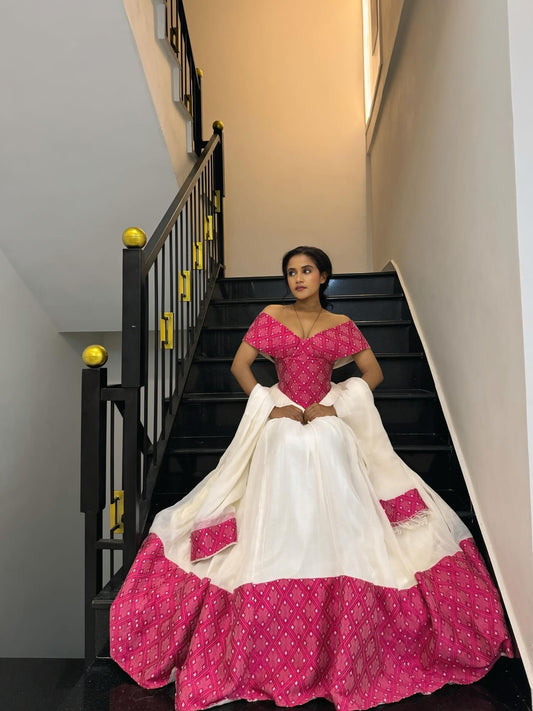Woman in a pink and white traditional habesha Dress sitting on a staircase.