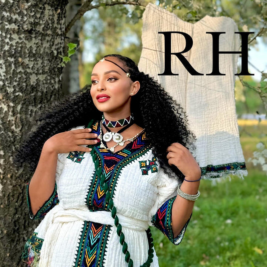 A woman outdoors wearing a white embroidered traditional-style Ethiopian National Dress with colorful geometric trim, standing beside a tree. A matching white textured garment is draped behind her, and large black letters 'RH' appear in the upper right.