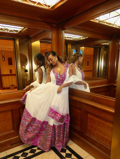 Woman in a colorful Habesha Wedding Dress standing in front of a mirror in an elevator.