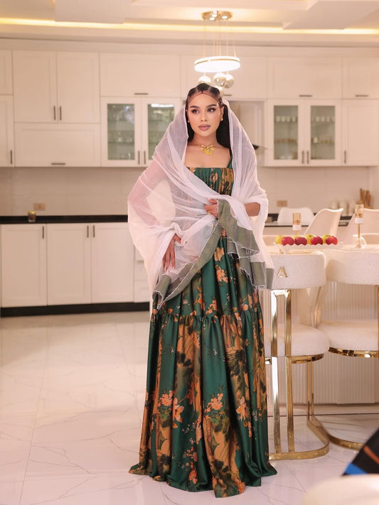 Woman in a green and gold traditional habesha  shiffion with a white scarf in a modern kitchen.
