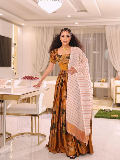 Woman in a traditional Gold Habesha shiffon Dress standing in a modern interior setting