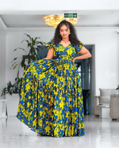 Woman wearing a blue and yellow floral Yellow and Green Shiffon Ethiopian Dress in an indoor setting