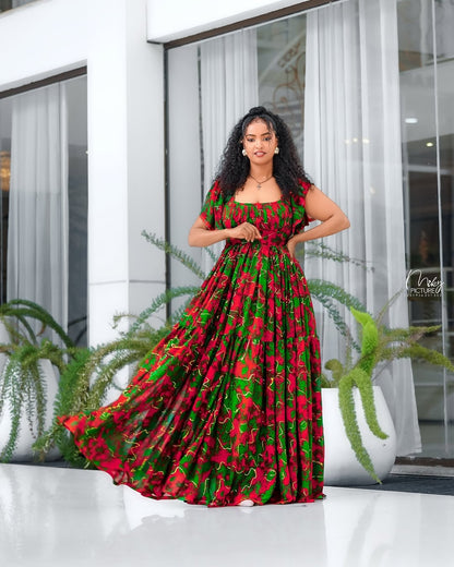 Woman wearing a red and green patterned Shiffon standing in front of a modern building entrance.