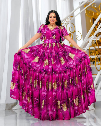 Woman in a vibrant pink habesha chiffion with gold patterns standing in a decorative interior setting.