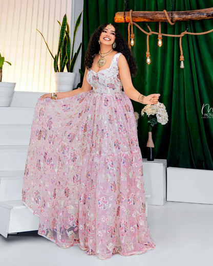 Woman in a floral Habesha Kemis posing in a decorated indoor setting with greenery and decor.