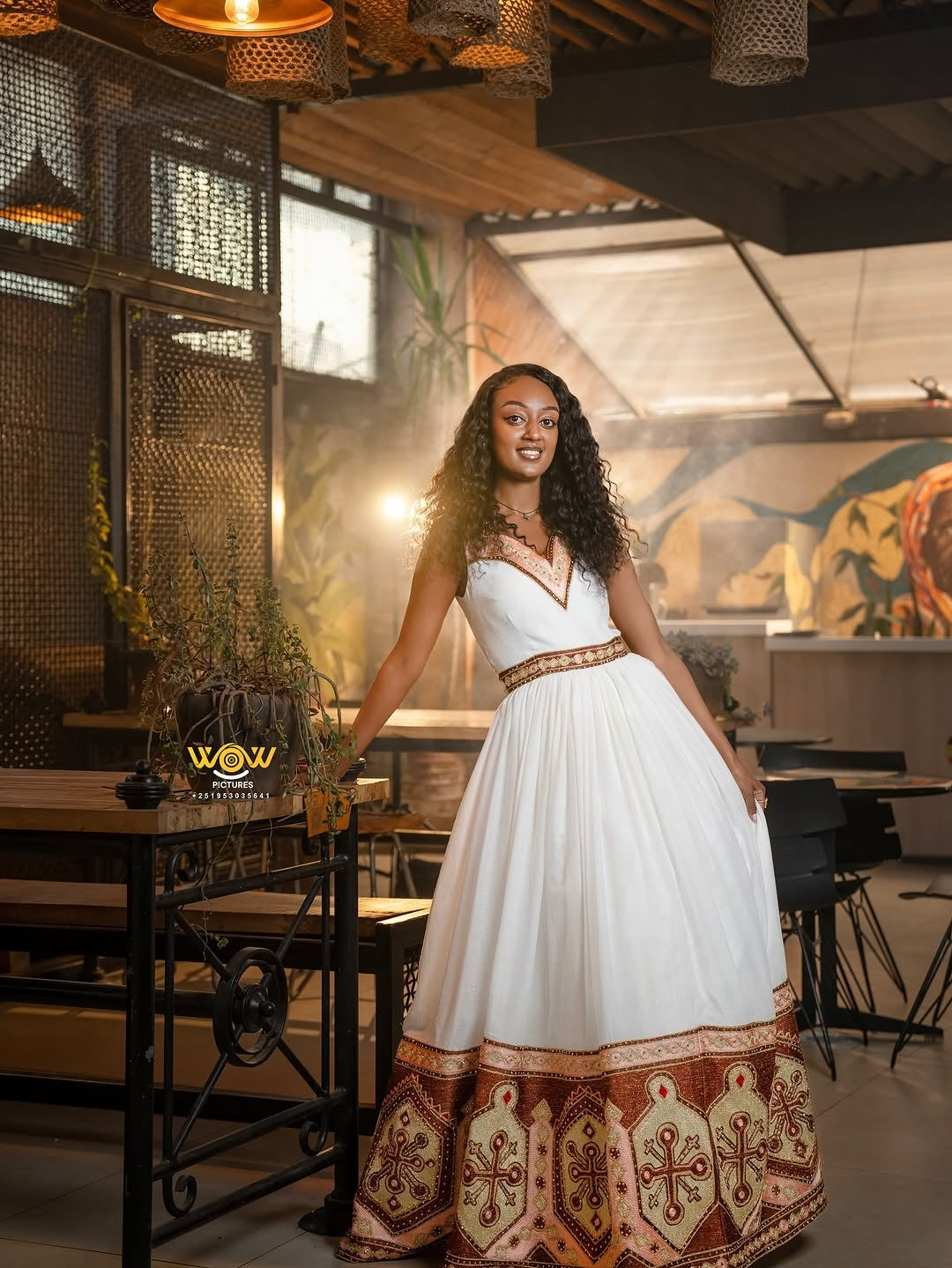 Woman in a white dress with brown patterns standing in a restaurant setting