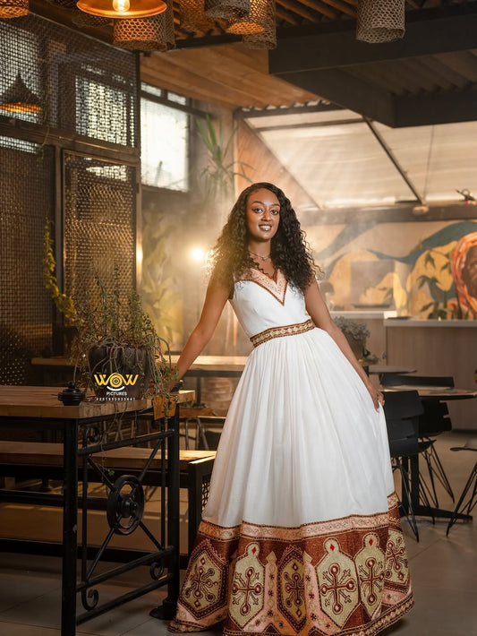Woman in a white dress with brown patterns standing in a restaurant setting