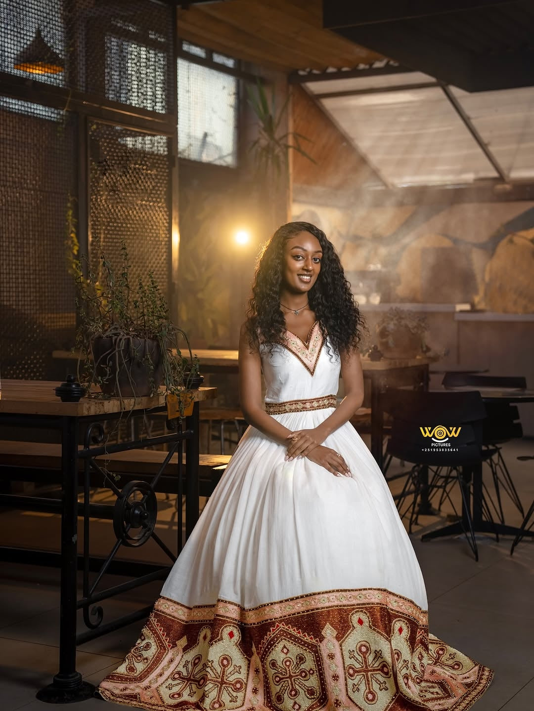 Woman in a white dress with red patterns standing in a restaurant setting